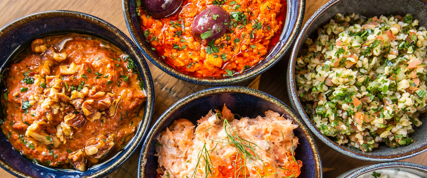 Array of dips and spreads served at Del Mar Naples: hummus, roasted red pepper, spicy feta, tzatziki, and tabbouleh.