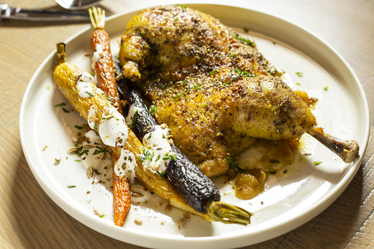 Roasted half chicken plated with roasted root vegetables.