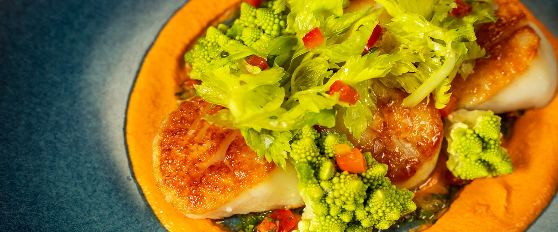 Plated Scallops served on roasted pepper purée, romanesco and preserved lemon.